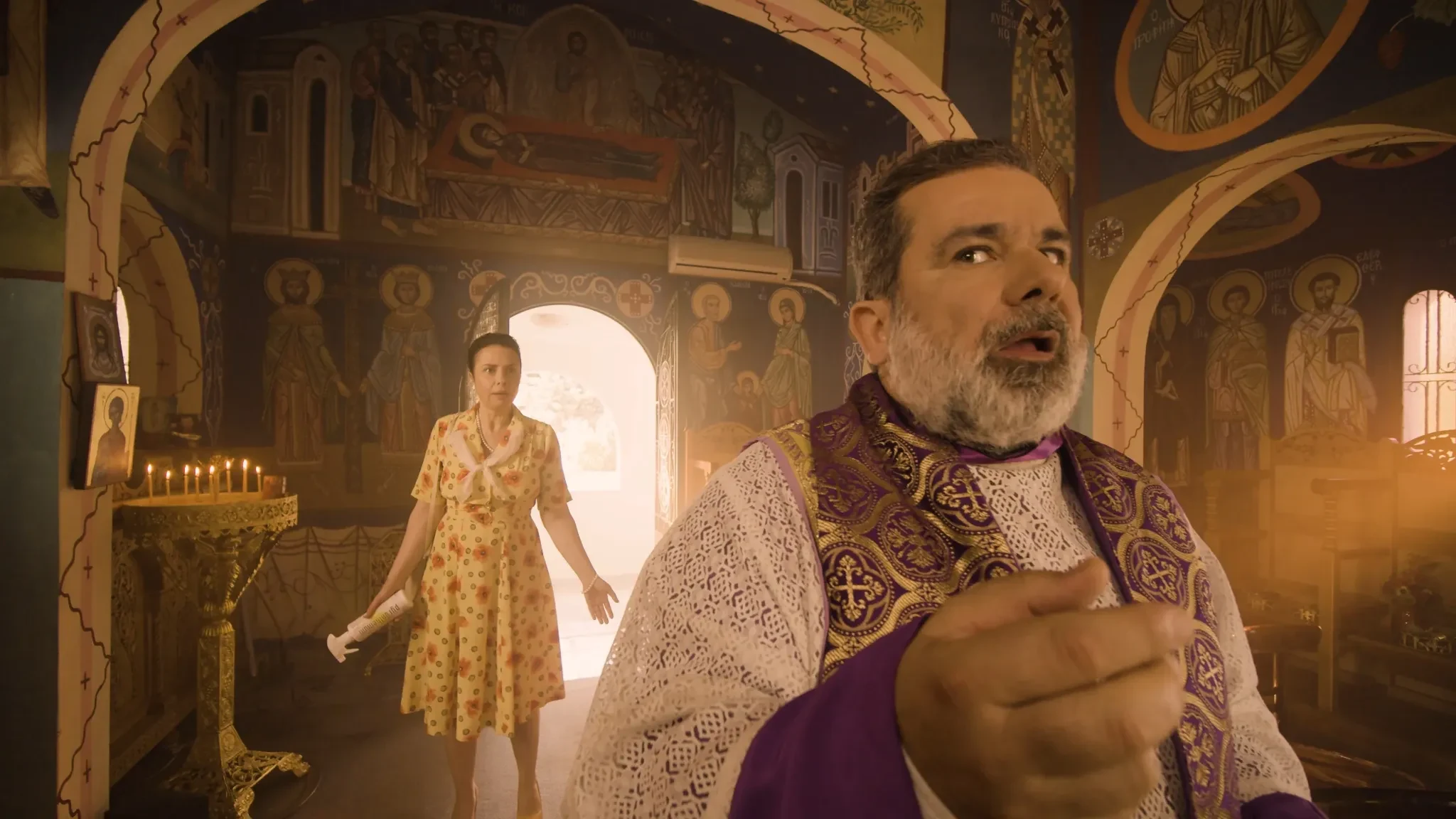Pyranthemum still of priest reacting in church as a woman enters carrying the pesticide product
