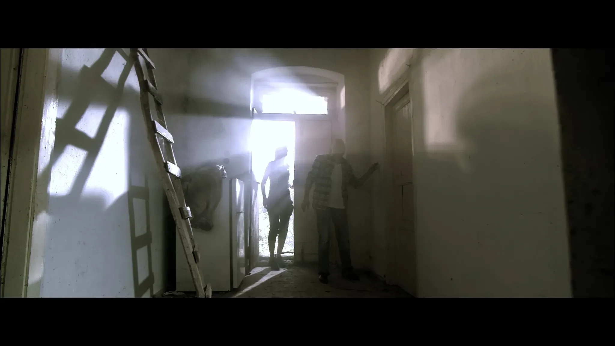 Sotiria still of couple entering a mountain village interior flooded with light