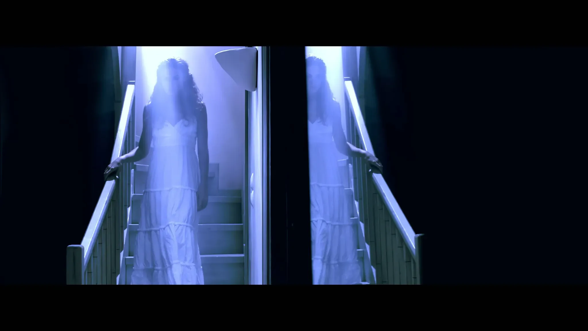 Sotiria still of woman in white dress on staircase seen through mirrored blue light
